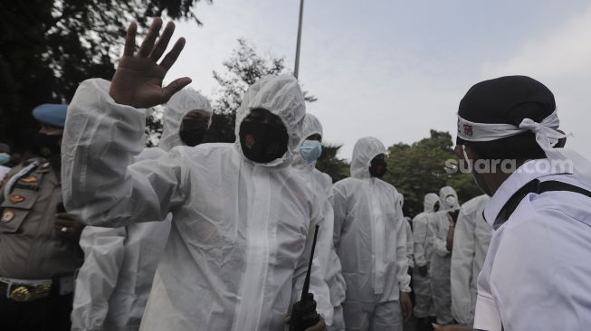 Polisi memakai baju hazmat memberi imbauan kepada massa yang mengikuti aksi solidaritas dukung Palestina di depan Kedubes AS, Jakarta, Selasa (18/5/2021). [Suara.com/Angga Budhiyanto]