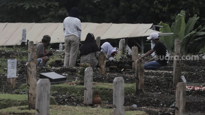 Warga berdoa di makam keluarganya saat melakukan ziarah kubur di pemakaman khusus COVID-19 di TPU Srengseng Sawah, Jakarta, Selasa (18/5/2021). [Suara.com/Angga Budhiyanto]