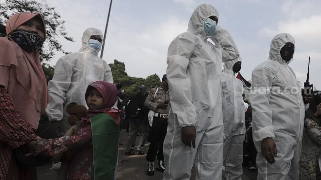 Polisi memakai baju hazmat memberi imbauan kepada massa yang mengikuti aksi solidaritas dukung Palestina di depan Kedubes AS, Jakarta, Selasa (18/5/2021). [Suara.com/Angga Budhiyanto]