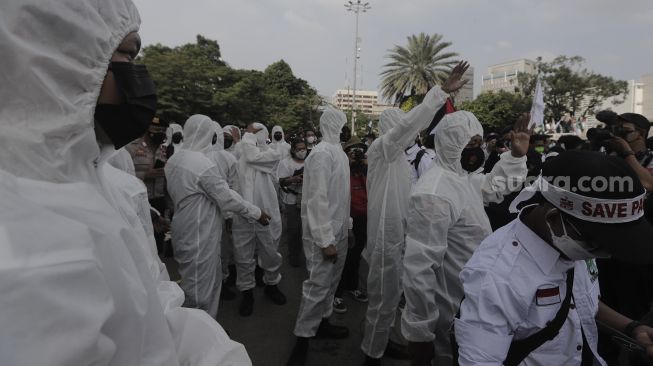 Polisi memakai baju hazmat memberi imbauan kepada massa yang mengikuti aksi solidaritas dukung Palestina di depan Kedubes AS, Jakarta, Selasa (18/5/2021). [Suara.com/Angga Budhiyanto]