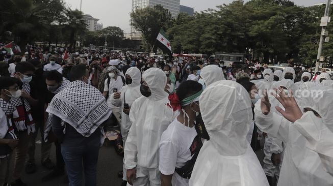 Polisi memakai baju hazmat memberi imbauan kepada massa yang mengikuti aksi solidaritas dukung Palestina di depan Kedubes AS, Jakarta, Selasa (18/5/2021). [Suara.com/Angga Budhiyanto]