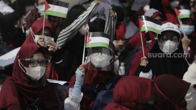 Massa aksi membawa miniatur bendera Palestina saat mengikuti aksi solidaritas dukung Palestina terkait kekerasan yang terjadi beberapa waktu lalu oleh Israel di depan Kedubes AS, Jakarta, Selasa (18/5/2021). [Suara.com/Angga Budhiyanto]