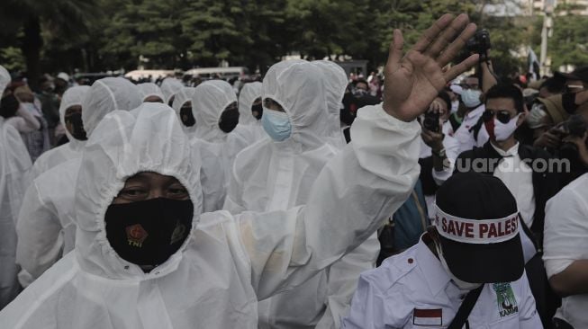 Polisi memakai baju hazmat memberi imbauan kepada massa yang mengikuti aksi solidaritas dukung Palestina di depan Kedubes AS, Jakarta, Selasa (18/5/2021). [Suara.com/Angga Budhiyanto]