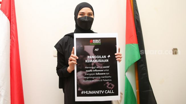 Aktria Zaskia Adya Mecca memegang poster sebagai bentuk simbolik dukungannya terhadap Palestina saat ditemui di Kedutaan Besar Palestina, Jakarta Pusat, Rabu (19/5/2021). [Suara.com/Alfian Winanto]