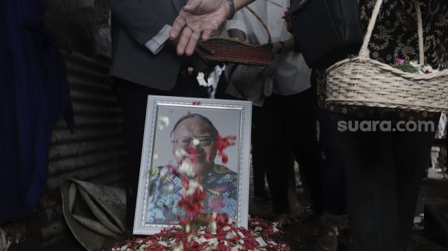 Keluarga menaburkan bunga ke atas pusara mantan Juru Bicara Presiden ke-4 Indonesia Abdurrahman Wahid (Gus Dur), Wimar Witoelar di Tempat Pemakaman Umum (TPU) Tanah Kusir, Jakarta, Rabu (19/5/2021). [Suara.com/Angga Budhiyanto]