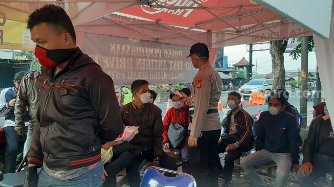 Para pemudik mengantre untuk mengikuti rapid test antigen gratis di Posko Sasak Jarang, Bekasi Timur, Rabu (19/5/2021). [Suara.com/Ummi Hadyah Saleh]