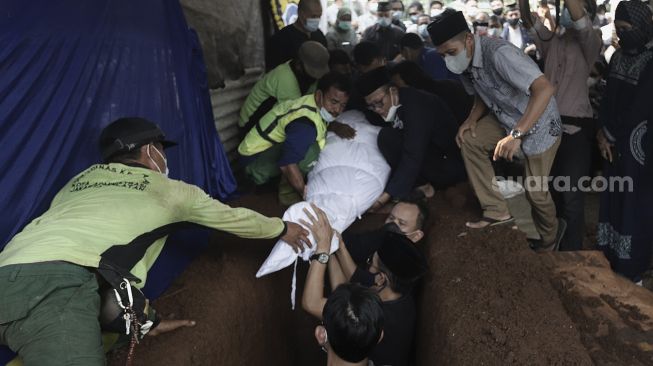 Keluarga dibantu petugas pemakaman menguburkan jenazah mantan Juru Bicara Presiden ke-4 Indonesia Abdurrahman Wahid (Gus Dur), Wimar Witoelar di Tempat Pemakaman Umum (TPU) Tanah Kusir, Jakarta, Rabu (19/5/2021). [Suara.com/Angga Budhiyanto]