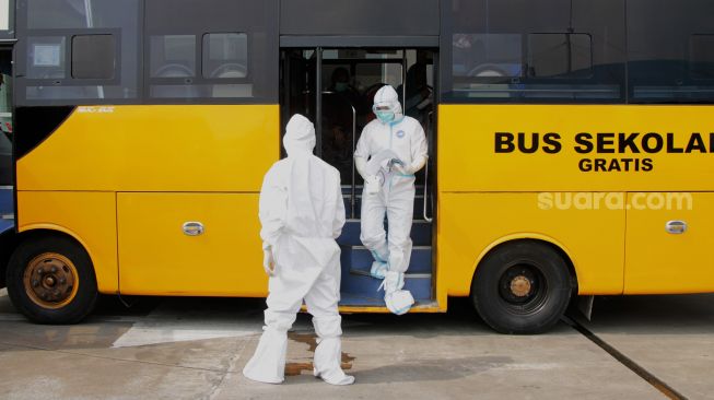 Petugas mengecek kondisi pemudik yang dinyatakan Positif di dalam Bus di Terminal Pulo Gebang, Jakarta, Rabu (19/5/2021).  [Suara.com/Dian Latifah]