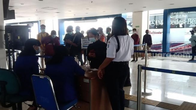 Petugas memeriksa dokumen berupa KTP dan surat keterangan bebas Covid-19 terhadap penumpang yang baru tiba di Terminal Pulo Gebang, Jakarta Timur, Rabu (19/5/2021). [Suara.com/Yosea Arga Pramudita]