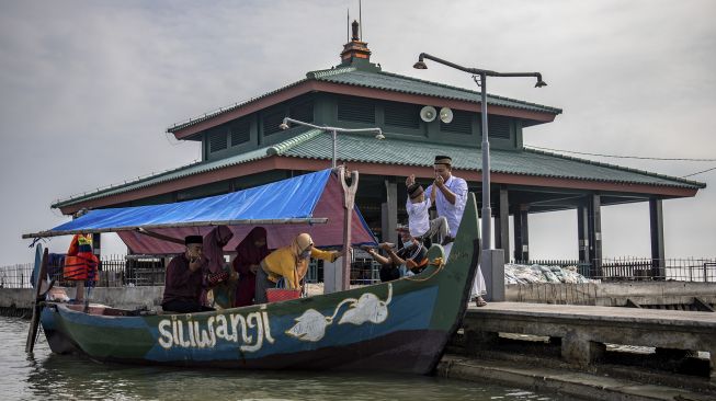 Sejumlah peziarah menaiki perahu untuk mengunjungi makam Simbah Kiai Abdullah Mudzakkir yang dijuluki 'Makam Terapung' di pesisir Desa Bedono, Sayung, Demak, Jawa Tengah, Kamis (20/5/2021). [ANTARA FOTO/Aji Styawan]