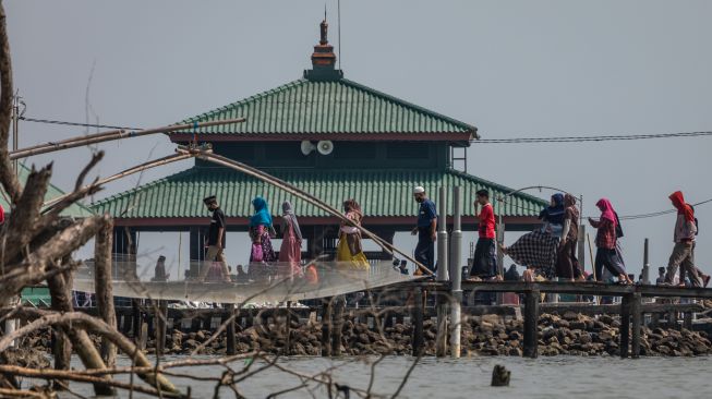 Sejumlah peziarah berjalan menuju makam Simbah Kiai Abdullah Mudzakkir yang dijuluki 'Makam Terapung' di pesisir Desa Bedono, Sayung, Demak, Jawa Tengah, Kamis (20/5/2021). [ANTARA FOTO/Aji Styawan]