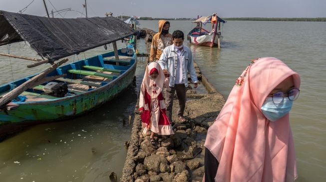 Sejumlah peziarah berjalan menuju makam Simbah Kiai Abdullah Mudzakkir yang dijuluki 'Makam Terapung' di pesisir Desa Bedono, Sayung, Demak, Jawa Tengah, Kamis (20/5/2021). [ANTARA FOTO/Aji Styawan]