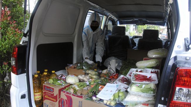 Pegawai Perumda Pasar Pakuan Jaya menggunakan hazmat untuk membagikan sembako di Perumahan Griya Melati, Kelurahan Bubulak, Kota Bogor, Jawa Barat, Kamis (20/5/2021). [ANTARA FOTO/Arif Firmansyah]