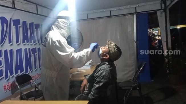 Petugas melakukan tes swab antigen terhadap pemudik di Posko Penyekatan Jatiuwung, Kota Tangerang, Rabu (19/5/2021) malam. [Suara.com/Jehan Nurhakim]