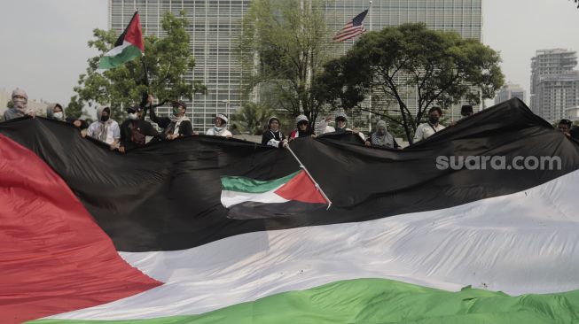 Sejumlah massa aksi membentangkan bendera Palestina saat mengikuti aksi solidaritas dukung Palestina terkait kekerasan yang terjadi beberapa waktu lalu oleh Israel di depan Kedubes AS, Jakarta, Jumat (21/5/2021). [Suara.com/Angga Budhiyanto]