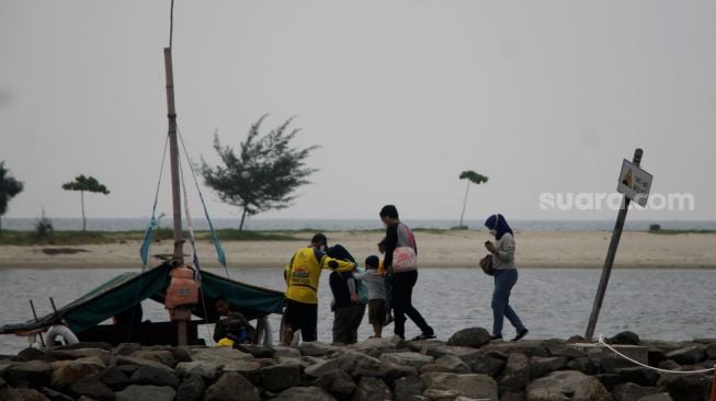 Pengunjung berjalan di kawasan Pantai Ancol, Jakarta, Sabtu (22/5/2021). [Suara.com/Dian Latifah]