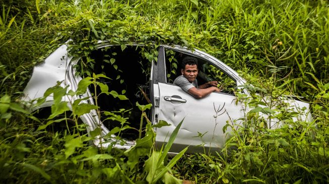 Warga berpose di bangkai mobil yang ditinggal pemiliknya di Desa Banjarsari, Lebak, Banten, Selasa (9/2/2021).