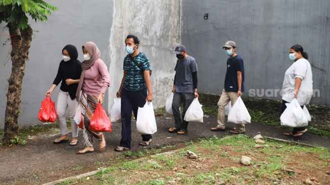 Warga mendistribusikan makanan dan bahan pokok untuk diberikan kepada warga yang menjalani isolasi mandiri dan terdampak Covid-19 di RT 03/ RW 03, Cilangkap, Jakarta Timur, Minggu (23/5/2021). [Suara.com/Alfian Winanto]