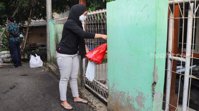 Warga mendistribusikan makanan dan bahan pokok untuk diberikan kepada warga yang menjalani isolasi mandiri dan terdampak Covid-19 di RT 03/ RW 03, Cilangkap, Jakarta Timur, Minggu (23/5/2021). [Suara.com/Alfian Winanto]