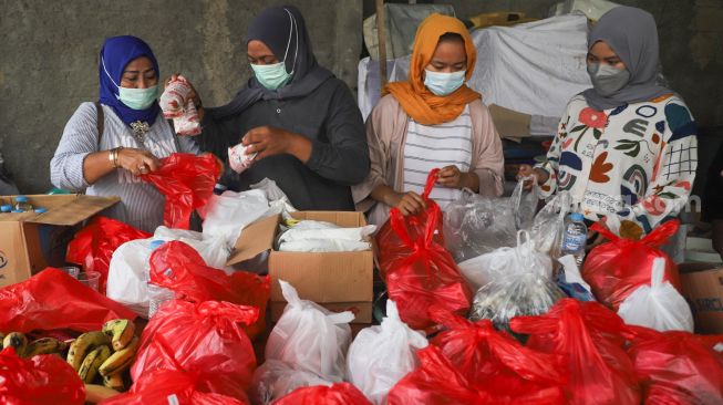 Warga menyiapkan makanan dan bahan pokok untuk diberikan kepada warga yang menjalani isolasi mandiri dan terdampak Covid-19 di RT 03/ RW 03, Cilangkap, Jakarta Timur, Minggu (23/5/2021). [Suara.com/Alfian Winanto]