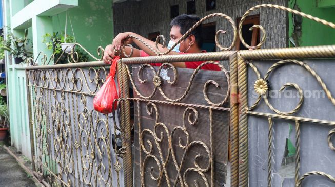 Warga yang menjalani isolasi mandiri dan terdampak Covid-19 menerima bantuan makanan dan bahan pokok di RT 03/ RW 03, Cilangkap, Jakarta Timur, Minggu (23/5/2021). [Suara.com/Alfian Winanto]