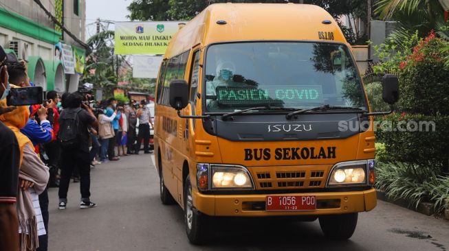 Kendaraan yang membawa warga RT 03 RW 03 berangkat menuju RSDC Wisma Atlet di Cilangkap, Jakarta Timur, Minggu (23/5/2021). [Suara.com/Alfian Winanto]