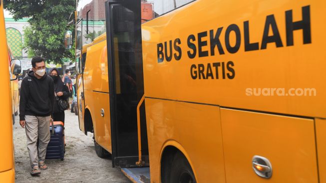 Warga RT 03 RW 03 menaiki mobil jemputan untuk selanjutnya dibawa ke RSDC Wisma Atlet di Cilangkap, Jakarta Timur, Minggu (23/5/2021). [Suara.com/Alfian Winanto]