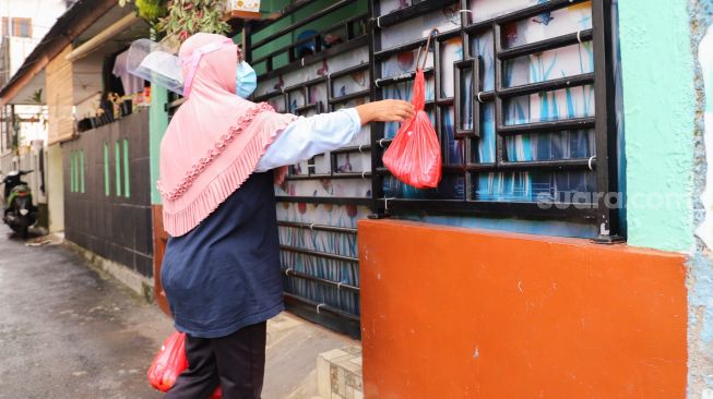 Warga mendistribusikan makanan dan bahan pokok untuk diberikan kepada warga yang menjalani isolasi mandiri dan terdampak Covid-19 di RT 03/ RW 03, Cilangkap, Jakarta Timur, Minggu (23/5/2021). [Suara.com/Alfian Winanto]