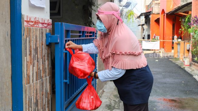 Warga mendistribusikan makanan dan bahan pokok untuk diberikan kepada warga yang menjalani isolasi mandiri dan terdampak Covid-19 di RT 03/ RW 03, Cilangkap, Jakarta Timur, Minggu (23/5/2021). [Suara.com/Alfian Winanto]