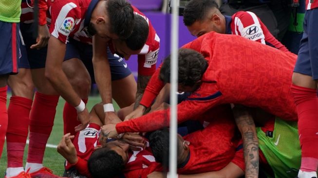 Para pemain Atletico Madrid merayakan gol penyerang Luis Suarez (bawah) pada laga Liga Spanyol 2020/2021 kontra Real Valladolid di Estadio Jose Zorilla, Sabtu (22/5/2021) malam WIB. [CESAR MANSO / AFP]