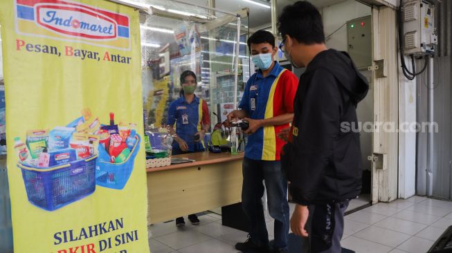 Pembeli berbelanja di minimarket dengan sistem Pesan Bayar Antar di Kawasan Cilangkap, Jakarta Timur, Minggu (23/5/2021). [Suara.com/Alfian Winanto]