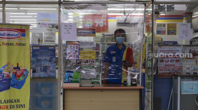 Karyawan minimarket menunggu pembeli di Kawasan Cilangkap, Jakarta Timur, Minggu (23/5/2021). [Suara.com/Alfian Winanto]