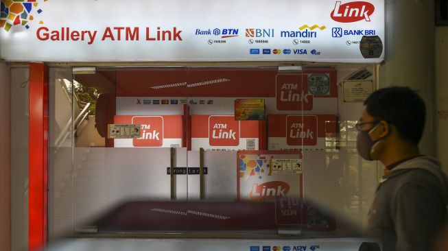 Warga melintas disamping mesin Anjungan Tunai Mandiri (ATM) Link di Jakarta, Minggu (23/5/2021). ANTARA FOTO/Galih Pradipta
