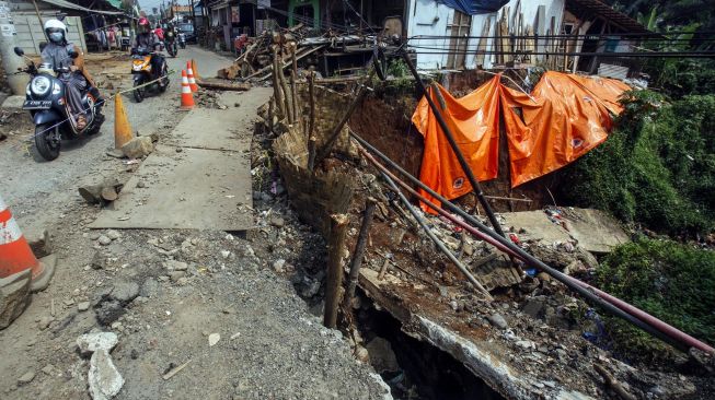 Pengendara sepeda motor melintas di akses jalan Kayu Manis-Cilebut yang longsor, Tanah Sareal, Kota Bogor, Jawa Barat, Senin (24/5/2021).  ANTARA FOTO/Yulius Satria Wijaya