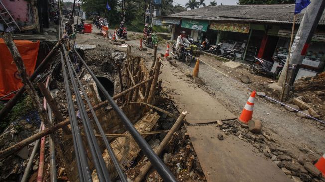 Pengendara sepeda motor melintas di akses jalan Kayu Manis-Cilebut yang longsor, Tanah Sareal, Kota Bogor, Jawa Barat, Senin (24/5/2021).  ANTARA FOTO/Yulius Satria Wijaya