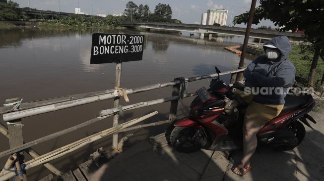 PSejumlah pengendara sepeda motor menunggu perahu eretan untuk menyeberangi Kali Cagak, Jakarta Utara, Selasa (25/5/2021). [Suara.com/Angga Budhiyanto]