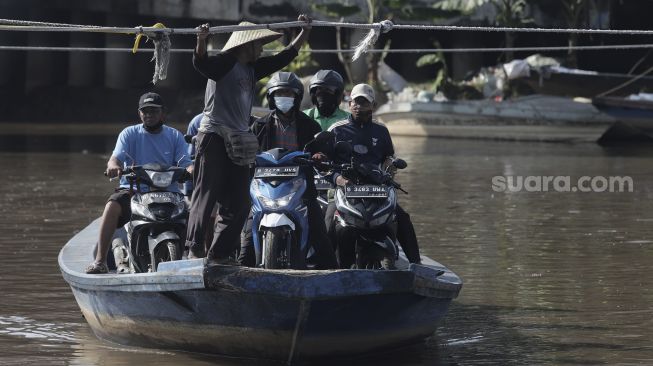 Sejumlah pengendara sepeda motor menggunakan perahu eretan untuk menyeberangi Kali Cagak, Jakarta Utara, Selasa (25/5/2021). [Suara.com/Angga Budhiyanto]