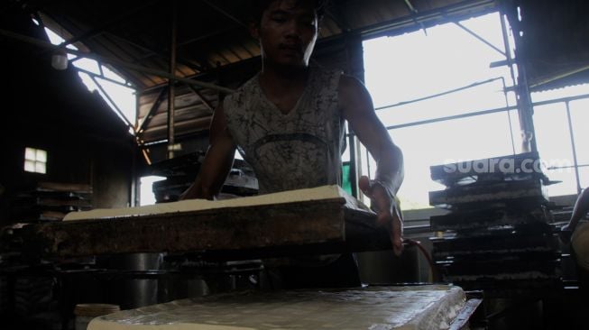 Pekerja menyelesaikan pembuatan tahu di pabrik tahu di jalan Satopati, Bantargebang, Bekasi, Selasa (25/5/2021).  [Suara.com/Dian Latifah]
