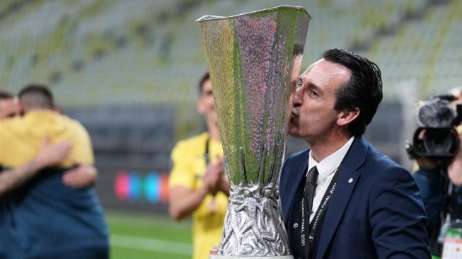 Pelatih Villarreal, Unai Emery mencium trofi Liga Europa 2020/2021 yang direngkuh timnya usai mengalahkan Manchester United dalam laga final di Stadion Miejski, Gdansk, Polandia, Kamis (27/5/2021) dini hari WIB. [Michael Sohn / POOL / AFP].