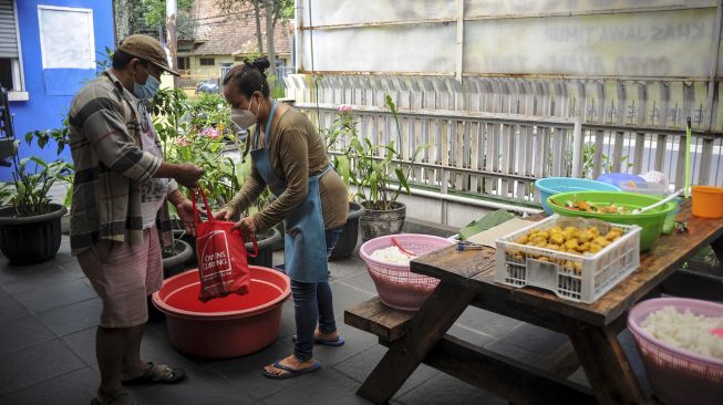 Seorang warga membeli nasi bungkus di posko gerakan nasi bungkus dua ribu di Jalan Natuna, Bandung, Jawa Barat, Kamis (27/5/2021). [ANTARA FOTO/Raisan Al Farisi]