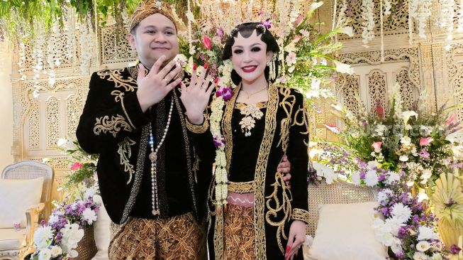 Pedangdut Nabilla Gomes dan suami, Muhammad Reza memamerkan cincin di jari manis mereka saat melangsungkan resepsi pernikahan di Aula Masjid Kubah Emas, Depok, Jawa Barat, Jumat (28/5/2021). [Suara.com/Alfian Winanto]