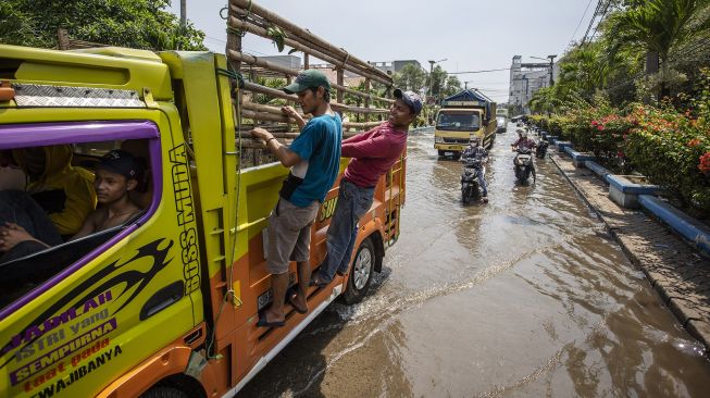 Warga menumpang truk saat melintasi banjir rob di kawasan Pelabuhan Perikanan Muara Baru, Jakarta, Jumat (28/5/2021). ANTARA FOTO/Dhemas Reviyanto

