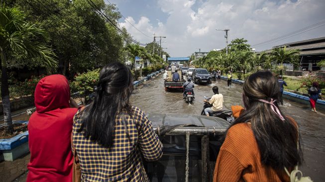 Warga menumpang mobil bak saat melintasi banjir rob di kawasan Pelabuhan Perikanan Muara Baru, Jakarta, Jumat (28/5/2021). ANTARA FOTO/Dhemas Reviyanto
