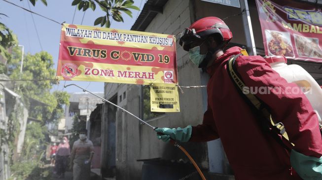 Petugas pemadam kebakaran menyemprotkan cairan disinfektan di Gang Usman Tepos, RT 004 RW 002 Kelurahan Srengseng Sawah, Jagakarsa, Jakarta Selatan, Jumat (28/5/2021). [Suara.com/Angga Budhiyanto]