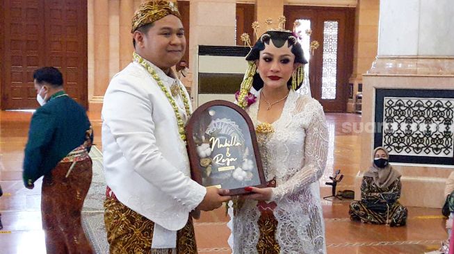 Pedangdut Nabila Gomes dan suaminya, Muhammad Reza usai melangsungkan akad nikah di Masjid Kubah Emas, Depok, Jawa Barat, Jumat (28/5/2021). [Suara.com/Alfian Winanto]