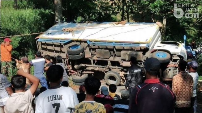 Warga bersama TNI-Polri saat membantu proses evakuasi truk terguling di jalan alternatif Jatim - Jateng tepatnya di Desa Gonggang, Kecamatan Poncol, Magetan, Jumat (28/5/2021). [Beritajatim.com]