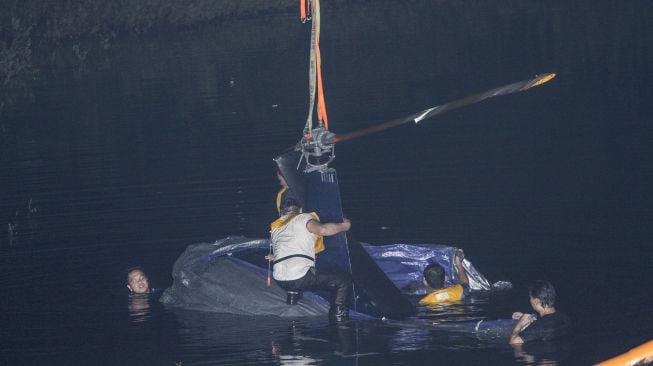 Petugas KNKT melakukan proses evakuasi pengangkatan helikopter latih yang jatuh di Setu Rawa Jemblong, Buperta, Depok, Jawa Barat, Sabtu (29/5/2021) dini hari. [ANTARA FOTO/Asprilla Dwi Adha]