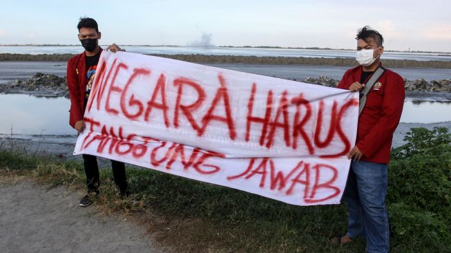 Mahasiswa yang tergabung dalam Ikatan Mahasiswa Muhammadiyah (IMM) Sidoarjo menggelar aksi di atas tanggul titik 21 Desa Siring, Porong, Sidoarjo, Jawa Timur, Sabtu (29/5/2021). ANTARA FOTO/Umarul Faruq