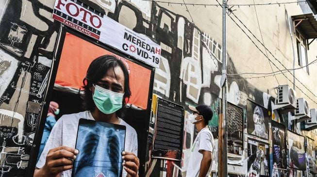 Warga melihat salah satu karya foto saat pameran fotografi bertajuk Meredah COVID-19 di kawasan Pasar Lama, Tangerang, Banten, Minggu (30/5/2021). ANTARA FOTO/Muhammad Adimaja