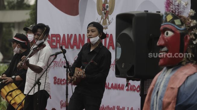 Pengamen jalanan bermain musik saat Peringatan Hari Lahir Pancasila di Kompleks Gelora Bung Karno, Jakarta, Selasa (1/6/2021). [Suara.com/Angga Budhiyanto]